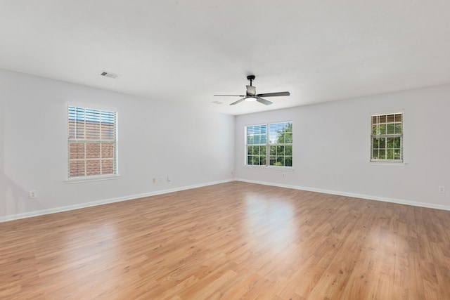 empty room with visible vents, light wood-style flooring, baseboards, and ceiling fan