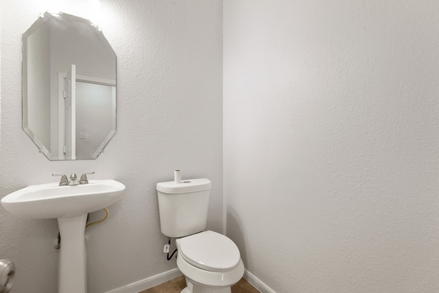 bathroom featuring a sink, baseboards, and toilet