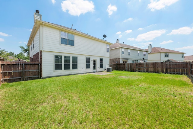 rear view of house featuring a lawn, a fenced backyard, and a chimney