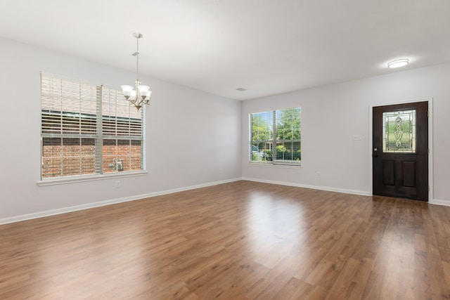 entrance foyer with an inviting chandelier, wood finished floors, and baseboards