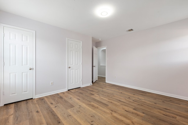 unfurnished bedroom with wood finished floors, visible vents, and baseboards