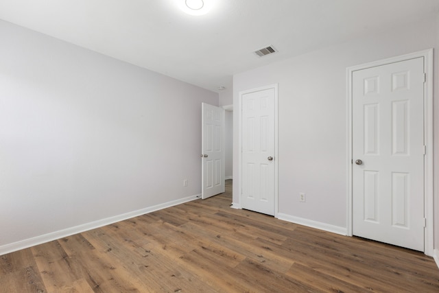 unfurnished bedroom featuring visible vents, baseboards, and wood finished floors