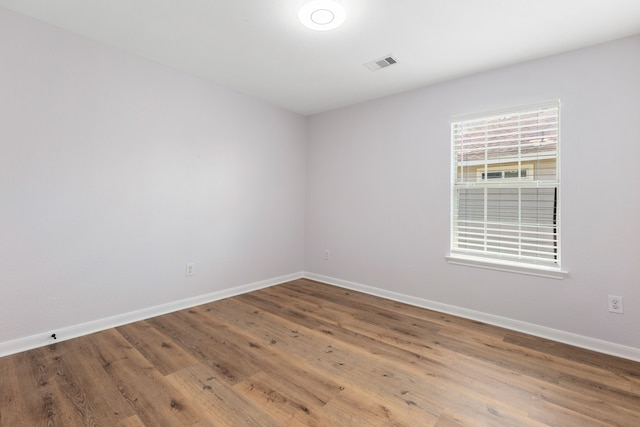 empty room with visible vents, baseboards, and wood finished floors