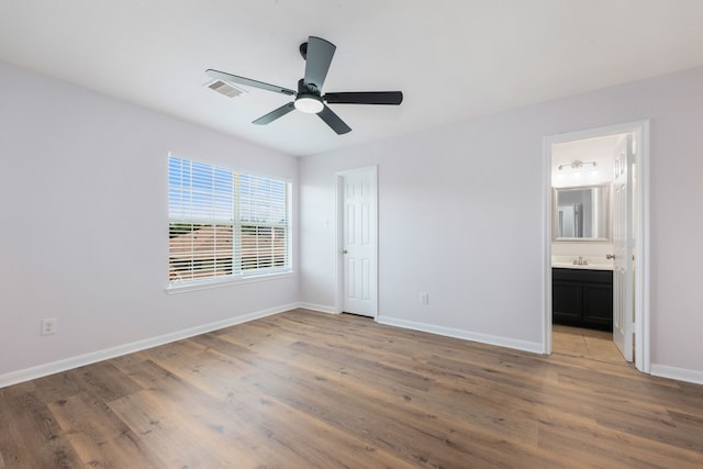 unfurnished bedroom featuring visible vents, ensuite bathroom, baseboards, and wood finished floors