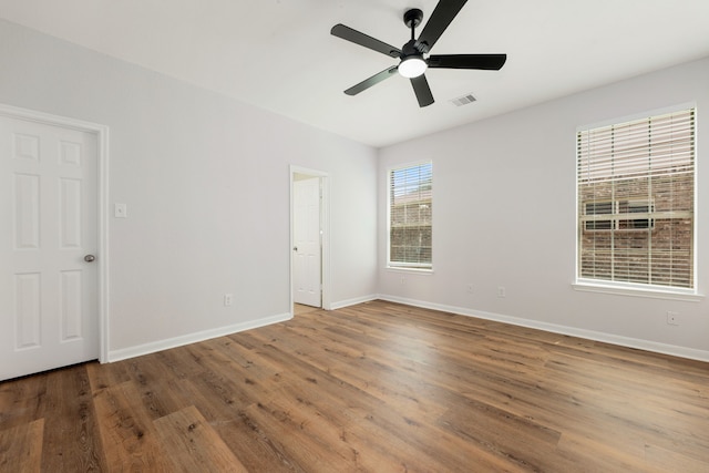 empty room featuring visible vents, baseboards, wood finished floors, and a ceiling fan