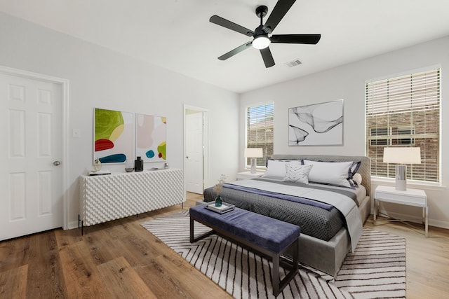 bedroom featuring visible vents, baseboards, ceiling fan, and wood finished floors