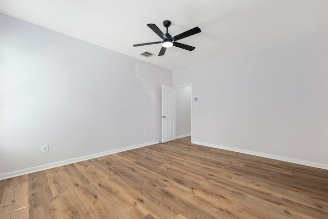 empty room featuring visible vents, wood finished floors, baseboards, and ceiling fan