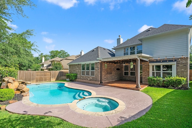 view of swimming pool featuring a patio area, a yard, and an in ground hot tub