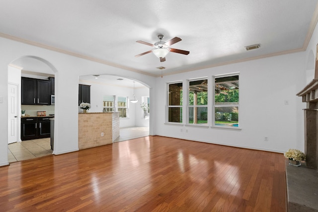 unfurnished living room with hardwood / wood-style flooring, ceiling fan, and crown molding