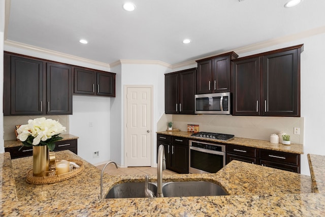 kitchen with backsplash, light stone counters, sink, and appliances with stainless steel finishes