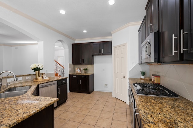 kitchen featuring sink, ornamental molding, light stone countertops, dark brown cabinets, and stainless steel appliances