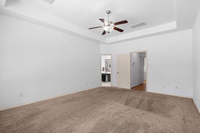 unfurnished room with ceiling fan, carpet floors, and a tray ceiling