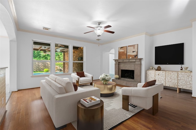 living room with a fireplace, wood-type flooring, ceiling fan, and ornamental molding