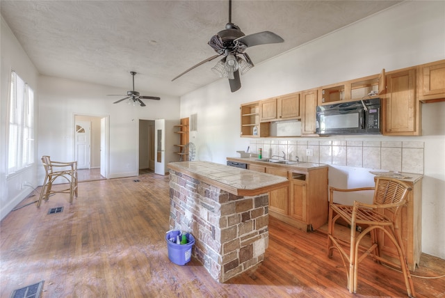 kitchen featuring hardwood / wood-style floors, tile counters, decorative backsplash, and a textured ceiling