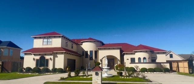 mediterranean / spanish-style home featuring a front lawn and a garage