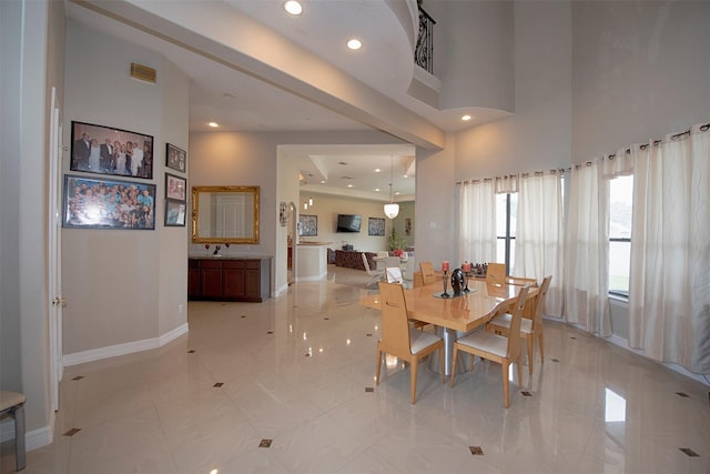 tiled dining area featuring a towering ceiling