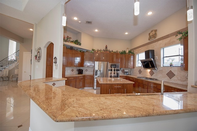 kitchen featuring hanging light fixtures, wall chimney range hood, and a center island