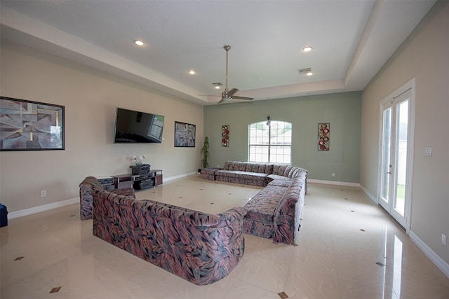 living room with ceiling fan and a tray ceiling