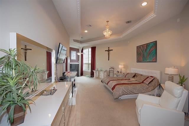 bedroom with a tiled fireplace, light carpet, a raised ceiling, and a notable chandelier