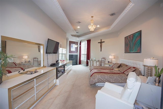 carpeted bedroom with a raised ceiling, a fireplace, and a chandelier