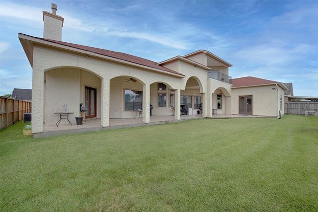 back of property with a lawn, central AC unit, ceiling fan, a patio area, and a balcony