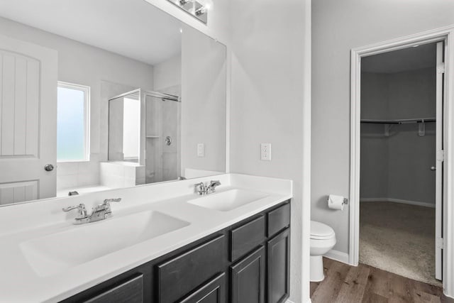 bathroom with hardwood / wood-style floors, vanity, toilet, and walk in shower