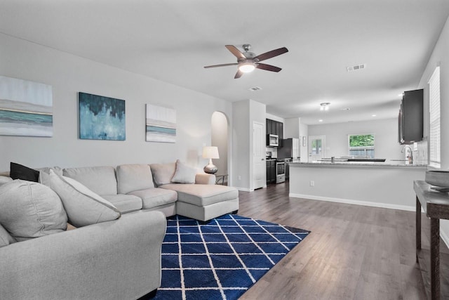 living room with ceiling fan and dark wood-type flooring