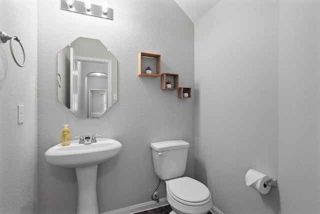 bathroom with toilet, lofted ceiling, and sink