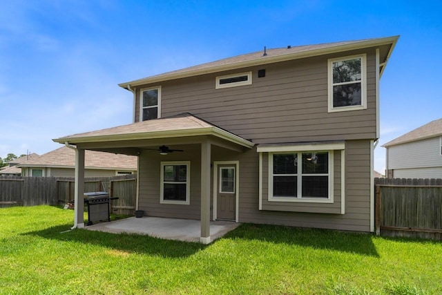 rear view of house with ceiling fan, a yard, and a patio