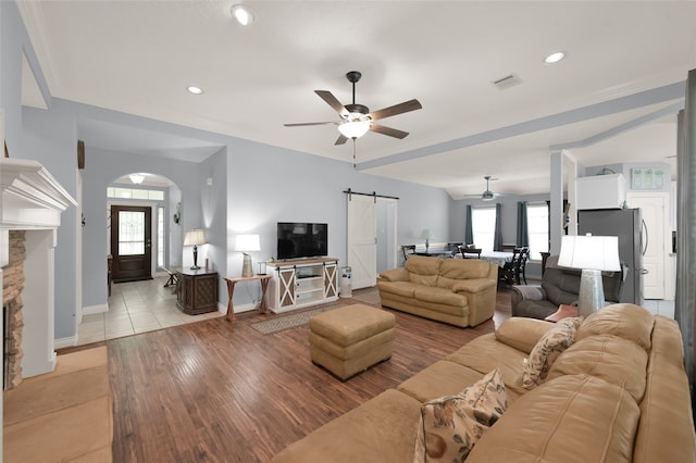 living room with a barn door, a wealth of natural light, ceiling fan, and light wood-type flooring