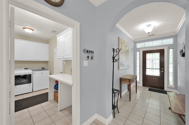 tiled entryway with crown molding and washing machine and clothes dryer