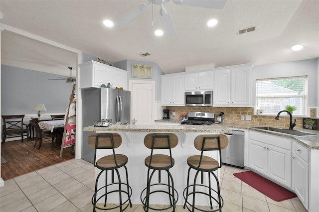 kitchen with light hardwood / wood-style flooring, white cabinets, backsplash, ceiling fan, and appliances with stainless steel finishes