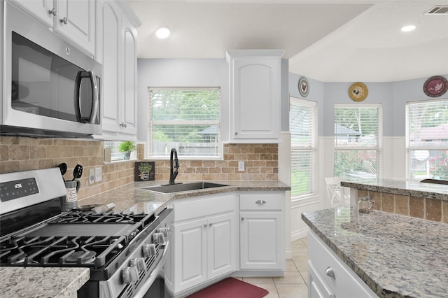 kitchen with appliances with stainless steel finishes, sink, backsplash, light tile patterned floors, and white cabinetry