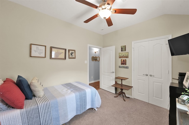 carpeted bedroom with vaulted ceiling, a closet, and ceiling fan