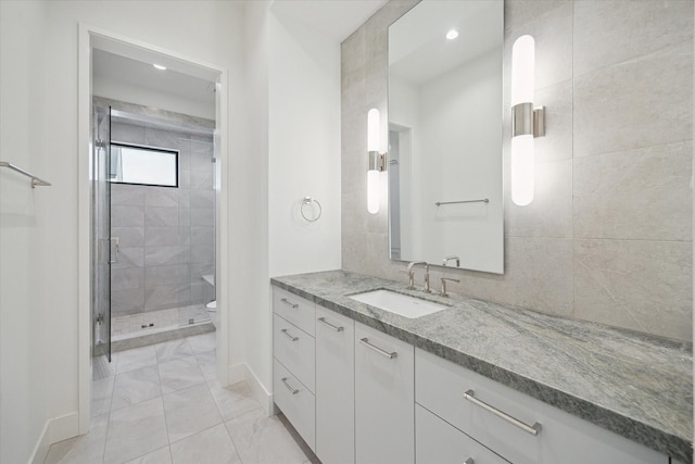 bathroom with a shower with door, vanity, and toilet