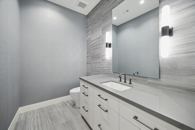 bathroom featuring vanity, toilet, and tile walls