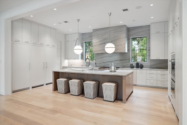 kitchen featuring hanging light fixtures, a center island, white cabinets, and backsplash