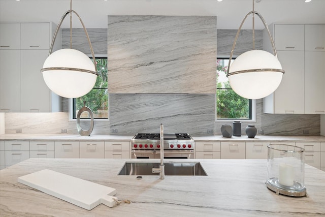 kitchen featuring range with two ovens, backsplash, white cabinets, and light stone counters