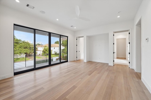 empty room with ceiling fan and light hardwood / wood-style flooring