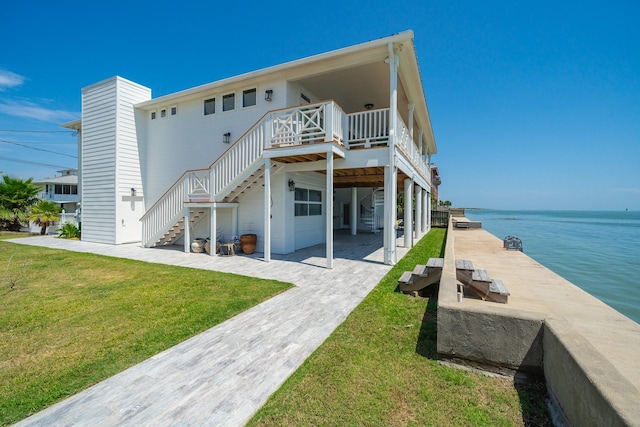 rear view of property with a water view, a lawn, and stairs