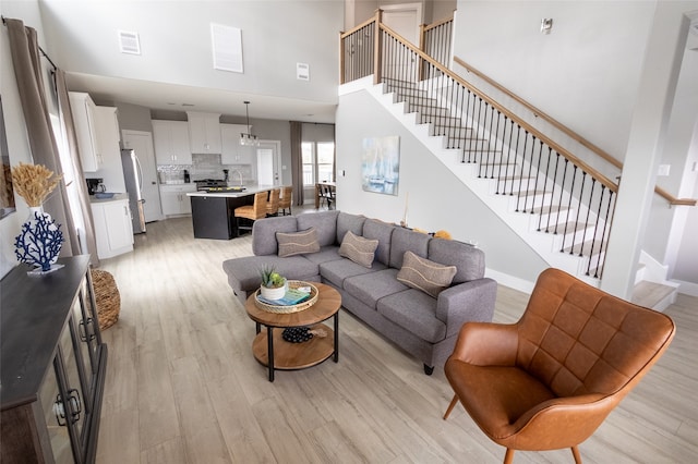 living room with a towering ceiling and light hardwood / wood-style flooring