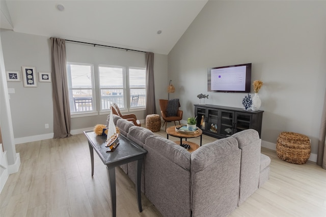 living room with high vaulted ceiling and light hardwood / wood-style flooring