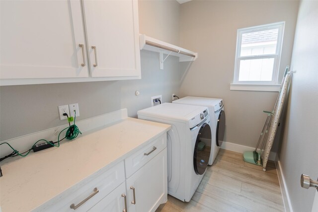 washroom featuring cabinets, hookup for a washing machine, washing machine and clothes dryer, and light hardwood / wood-style flooring