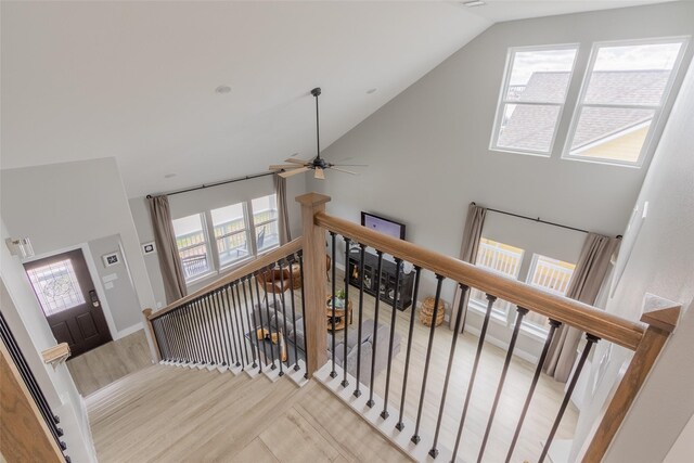 staircase featuring high vaulted ceiling, ceiling fan, and light hardwood / wood-style flooring