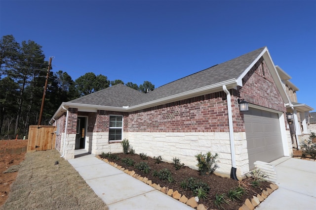 ranch-style home featuring stone siding, a shingled roof, an attached garage, and brick siding