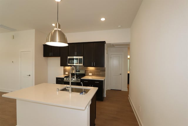 kitchen featuring appliances with stainless steel finishes, backsplash, wood finished floors, light countertops, and a sink