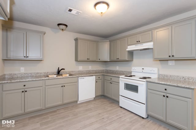 kitchen with sink, white appliances, light wood-type flooring, light stone countertops, and gray cabinetry