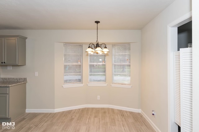 unfurnished dining area with a chandelier and light hardwood / wood-style floors