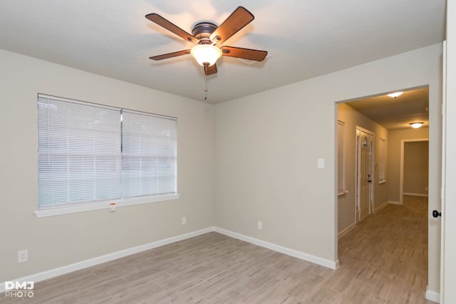 empty room with ceiling fan and light hardwood / wood-style flooring