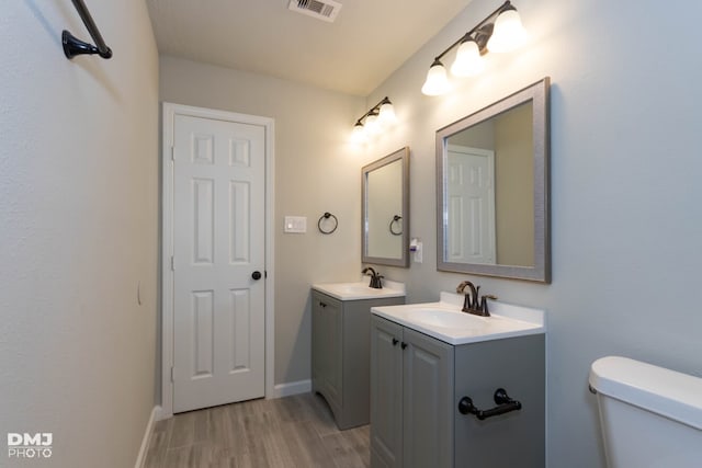 bathroom with wood-type flooring, toilet, and vanity